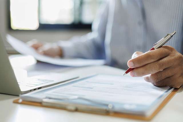 Person mit Dokumenten und Laptop