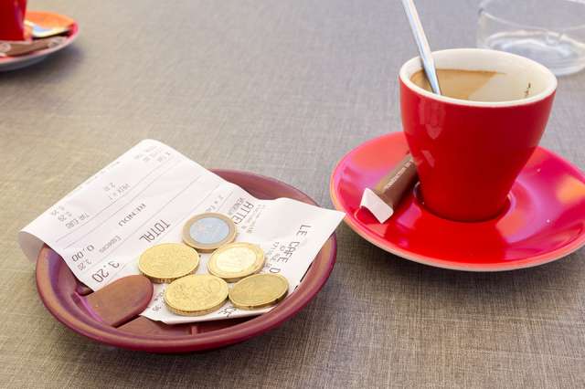 Kaffeetasse mit Rechnung und Münzen