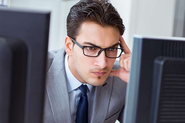 Person grübelt vor Bildschirmen